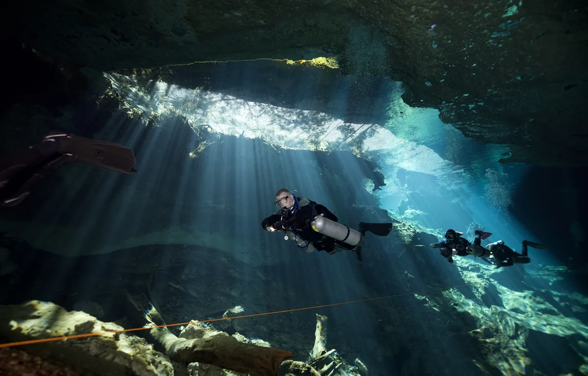 Andrew Grundy diving in a cenote cavern with light rays